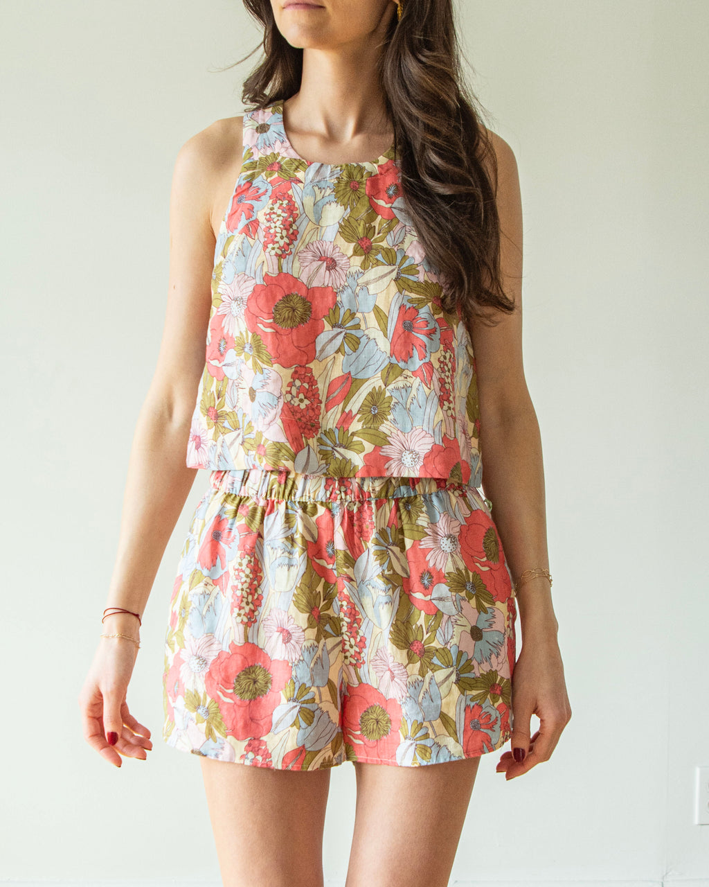 Woman wearing a floral romper against a plain background