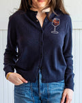Person wearing a navy cardigan with a wine glass design on a white background