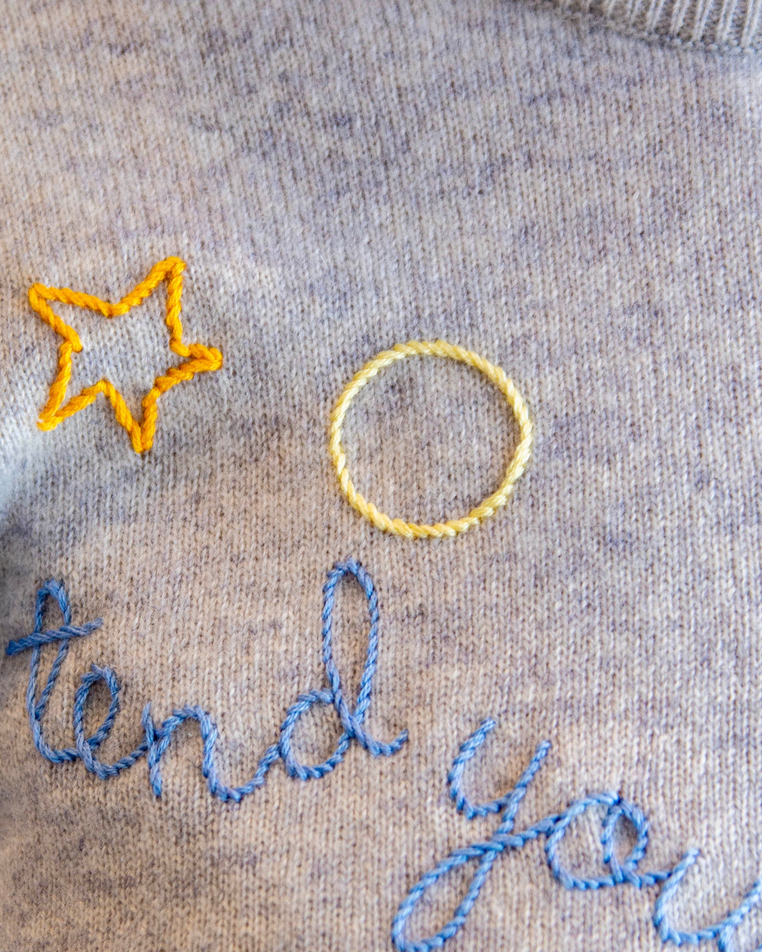 Embroidered text and star design on a gray fabric background